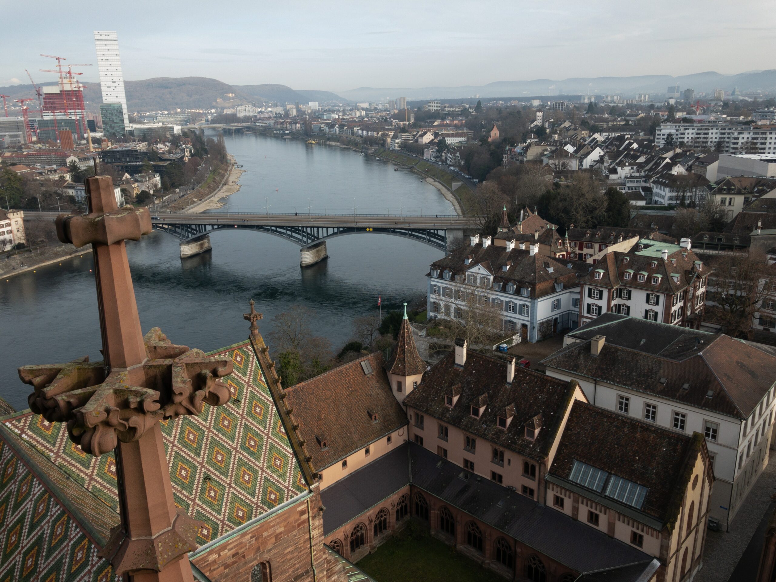 Entdecken Sie die malerische Aussicht auf Basel mit dem atemberaubenden Rhein, historischen Gebäuden und der modernen Architektur im Hintergrund – ein perfektes Beispiel für die Vereinigung von Tradition und Fortschritt in der Schweiz.